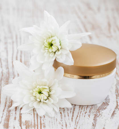 container of moisturizing face cream and white chrysanthemumの写真素材