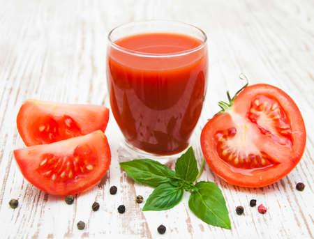glass of fresh tomato juice and some fresh tomatoesの写真素材