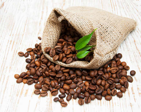 Coffee beans on burlap sack on a wooden backgroundの写真素材