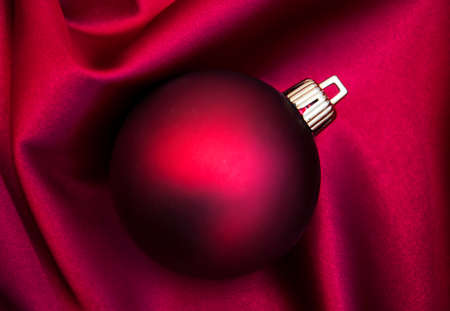 Christmas bauble on the red silk backgroundの写真素材