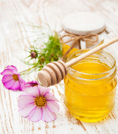 Glass pot of sweet honey with flowers on wooden tableの写真素材