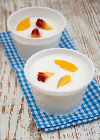 Yougurt with peaches on a wooden backgroundの写真素材