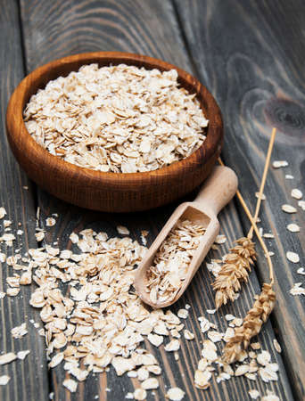 Wooden bowl with oat on a wooden background