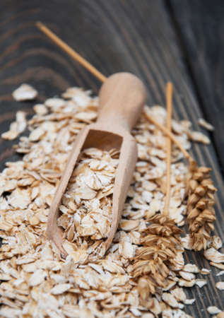 Wooden scoop with oat on a wooden backgroundの写真素材