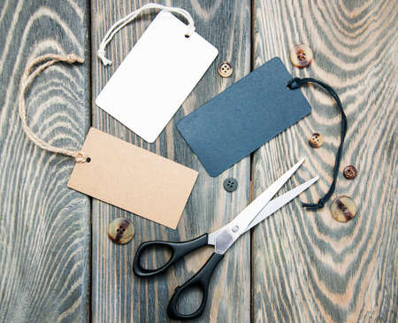 Paper tags, scissors and buttons on the wooden tableの写真素材