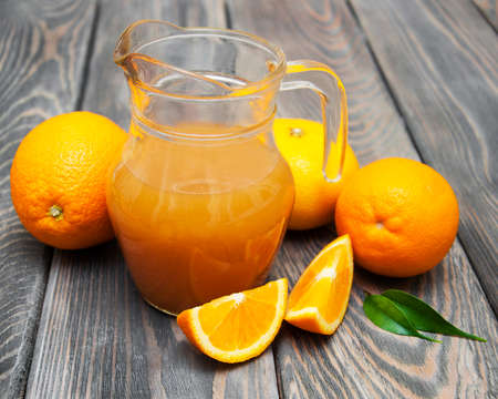 Orange juice in pitcher and fresh orangesの写真素材