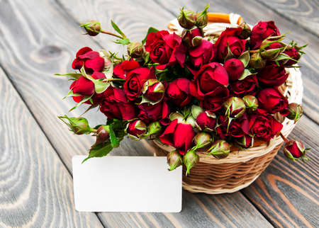 Basket with red roses on a wooden  backgroundの写真素材