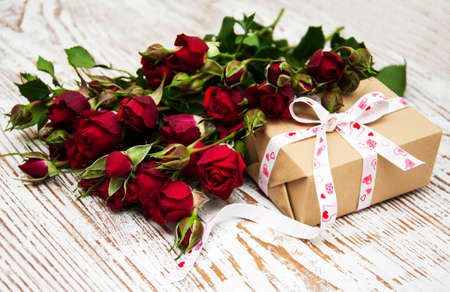 Red roses  and gift box on a wooden backgroundの写真素材