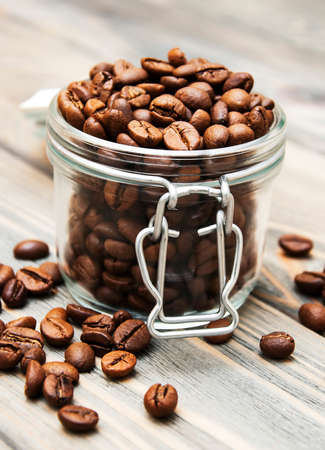 glass jar full of coffee beans on a wooden backgroundの写真素材
