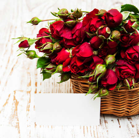 Basket with red roses on a wooden  backgroundの写真素材