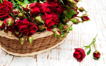 Basket  with red roses on a wooden  backgroundの写真素材
