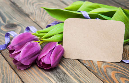 Purple tulips with a card on a old wooden backgroundの写真素材