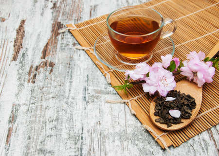 Cup of tea and pink sakura blossom on a old wooden background