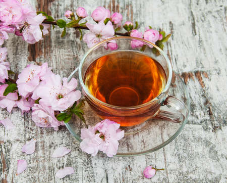 Cup of tea and pink sakura blossom on a old wooden backgroundの写真素材