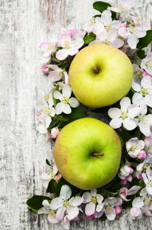 apples  and apple tree blossoms on a old wooden tableの写真素材