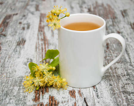 Cup of herbal tea with linden flowers on a old wooden backgroundの写真素材