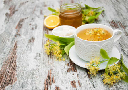 cup of herbal tea with linden flowers on a old wooden backgroundの写真素材