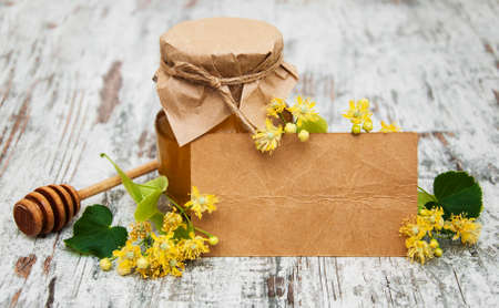 jar of honey and linden flowers with tag on a wooden backgroundの写真素材