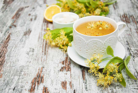 cup of herbal tea with linden flowers on a old wooden backgroundの写真素材
