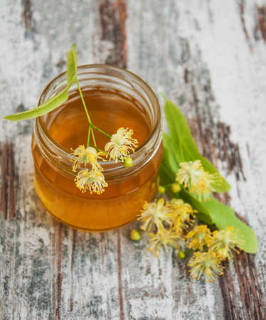 Jar with honey and linden flowers on a wooden backgroundの写真素材