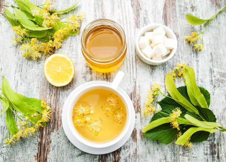 cup of herbal tea with linden flowers on a old wooden background