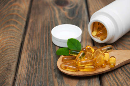 fish oil capsules in a spoon on a wooden backgroundの写真素材