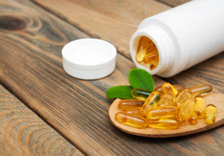 fish oil capsules in a spoon on a wooden backgroundの写真素材