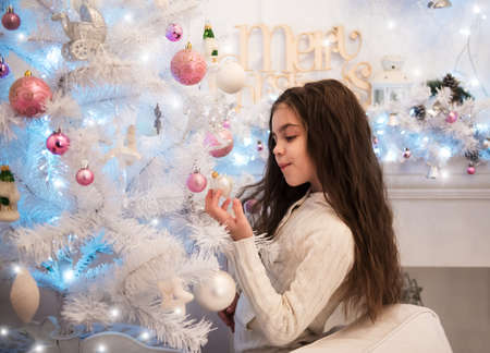 little girl decorating christmas tree in homeの写真素材