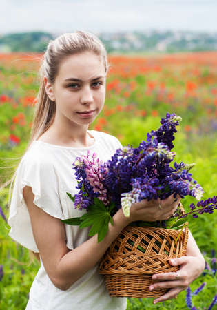 beautiful girl with basket of lupine flowers in handsの写真素材