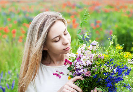 Beautiful blonde girl holding a bouquet of wildflowersの写真素材