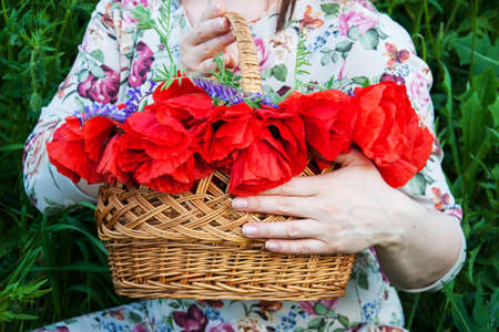 woman holding a basket with poppy flowersの写真素材