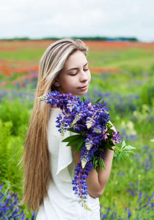 beautiful girl with bouquet of lupine flowers in handsの写真素材