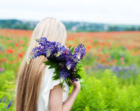beautiful girl with bouquet of lupine flowers in handsの写真素材