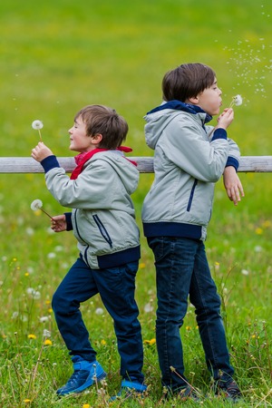Two boys leaning over a rustic wooden fenceの写真素材