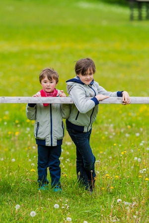 Two boys leaning over a rustic wooden fenceの写真素材