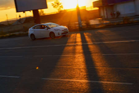 Car driving fast in the city. The sunset with beautiful sun rays in city.の写真素材