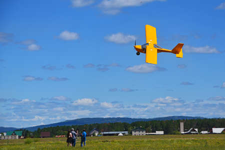 A small sports plane flies at a low altitude. Man takes flight on video. Air stunt plane.の写真素材