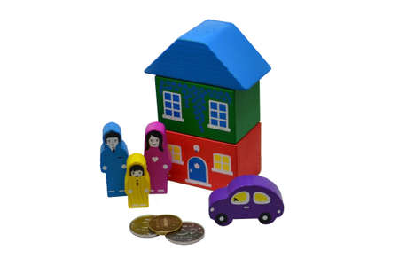 Miniature home, family and car standing near metal money on white background, Save money for prepare in the future and real estate concept or a loan for a car.Isolated over white background. Wooden toys.の写真素材