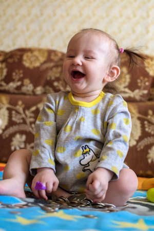 Happy girl with coins. Baby playing with coinsの写真素材