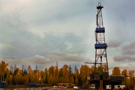 The oil drilling rig in a beautiful mixed autumn forest on a cloudy dayの写真素材