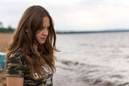 A young caucasian white woman sitting on a beach watching at the waterの写真素材