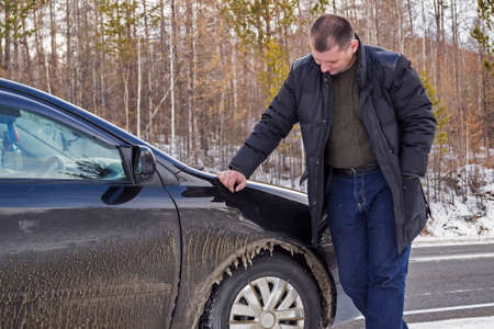 The driver looks at the car,covered with ice in cold weatherの写真素材
