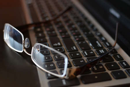 Close-ups on glasses on laptop - office life. Glasses on the laptop's keyboard. Close up.の写真素材