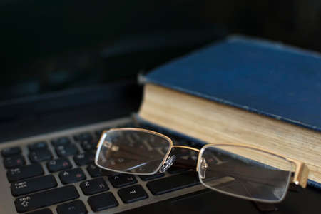 Glasses and the book on the laptop's keyboard. Close up.の写真素材