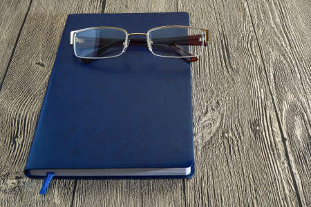 notepad and glasses on wooden backgroundの写真素材
