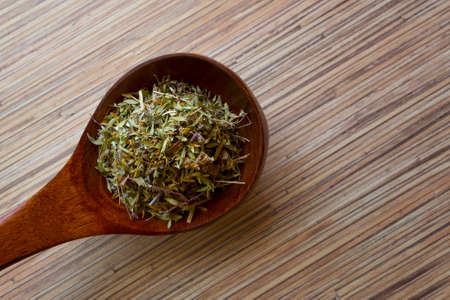 Healing herbs in wooden spoon on table closeupの写真素材