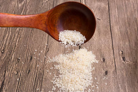Rice is poured from the wooden spoonの写真素材
