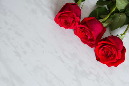 Three roses laying in diagonal group on the marble background. Space for text.の写真素材