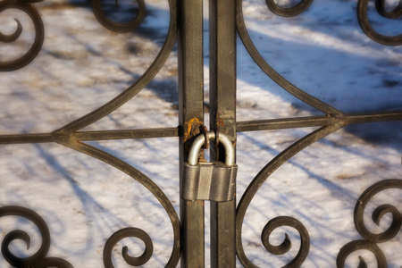 Padlock hanging on a decorative metal gate