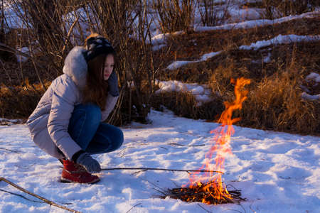 Young girl plays with bonfire during winter picnic.